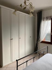 ペスキエーラ・デル・ガルダにあるLa Rosa del Gardaの白いキャビネット、ベッド、シャンデリアが備わるベッドルーム1室が備わります。