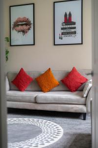 a living room with a couch with red and orange pillows at 4 Bedrooms Homely House - Sleeps 6 Comfortably with 6 Double Beds,Glasgow, Free Street Parking, Business Travellers, Contractors, & Holiday-Goers, Near All Major Transport Links in Glasgow & City Centre in Glasgow