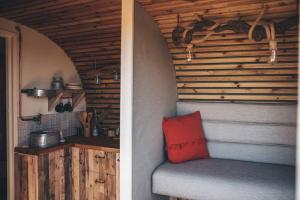 two pictures of a room with a bench and a kitchen at 'Cinnabar Nest' Remote Off-Grid Eco Cabin in Sedgefield