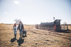 a man and a woman walking in a field with luggage at 'Cinnabar Nest' Remote Off-Grid Eco Cabin in Sedgefield