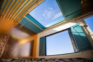 a room with two windows in a room with a bed at 'Cinnabar Nest' Remote Off-Grid Eco Cabin in Sedgefield
