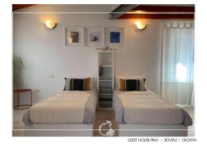 2 camas en una habitación con paredes blancas en Guest House Pina, en Rovinj