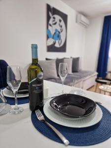 a table with a plate and a bottle of wine at Apartman Astra in Sremska Mitrovica