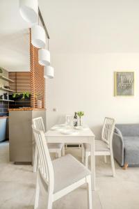 a white dining room with a white table and chairs at Łódź Retreat Apartments - Terrace, Garden & Parking - by Rentujemy in Łódź