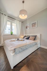 a white bedroom with a large bed in a room at Łódź Retreat Apartments - Terrace, Garden & Parking - by Rentujemy in Łódź