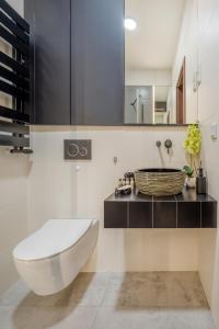 a bathroom with a white toilet and a sink at Łódź Retreat Apartments - Terrace, Garden & Parking - by Rentujemy in Łódź