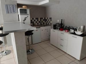 a kitchen with white cabinets and a white refrigerator at La maison des roses in Le Puy-en-Velay