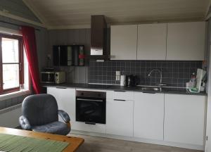 a kitchen with white cabinets and a chair and a sink at Svensby Tursenter in Svensby