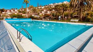 een groot zwembad met palmbomen en huizen bij Click&Guest - Red Rock Apartment in Maspalomas in Playa del Inglés