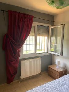 a bedroom with a red curtain and two windows at George Garden in Nea Michaniona