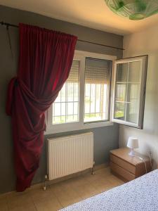 ネア・ミカニオーナにあるGeorge Gardenの赤いカーテンと2つの窓が備わるベッドルーム1室