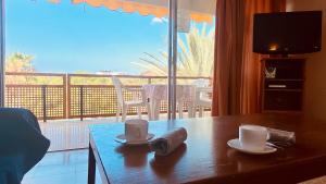 een kamer met een tafel met twee kopjes en een balkon bij Click&Guest - Red Rock Apartment in Maspalomas in Playa del Inglés