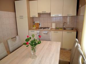 une cuisine avec une table et un vase de fleurs. dans l'établissement Apartman Tomić, à Korenica