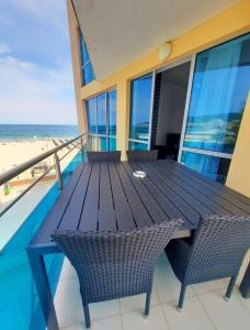 einen Holztisch und Stühle auf einem Balkon mit Strandblick in der Unterkunft Apartment "Palace" in Sonnenstrand