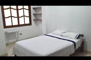 a white bed in a white room with a window at Casa de playa Palmeras in Tumbes