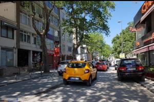 Une petite voiture jaune qui descend dans une rue de la ville dans l'établissement Bostanci cozy excellent location flat, à Istanbul