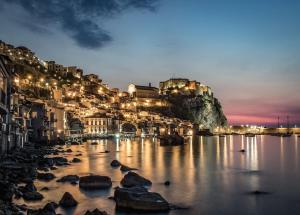 uma vista para uma cidade à noite com pedras na água em Stella Marina em Scilla