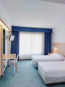 Cette chambre comprend deux lits et un bureau. dans l'établissement Hotel Costa Atlántica, à Arteixo