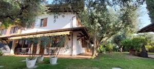 a large white house with trees in the yard at Elisa Holidays in Puegnago +26 photos