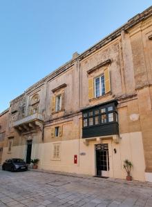 un vieux bâtiment avec une voiture garée devant lui dans l'établissement Palazzo del Prelato, à Mdina