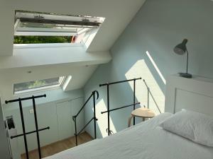 a bedroom with a white bed and a window at La Maison des Sources in Brussels