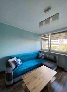 sala de estar con sofá azul y mesa de madera en Apartament przy Parku Śląskim, en Katowice