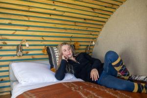 Una mujer está acostada en una cama en 'Pipistrelle' Remote Off-Grid Micro Cabin (No Kitchen), en Sedgefield