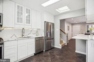 uma cozinha com armários brancos e um frigorífico de aço inoxidável em 5 bedroom w/ indoor pool/hotub em Silver Spring
