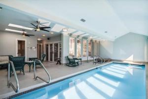 a swimming pool in a house with chairs and a table at 5 bedroom w/ indoor pool/hotub in Silver Spring