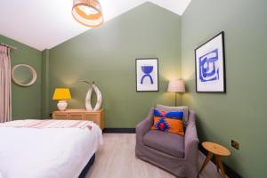 a bedroom with a bed and a chair at Hailes - a newly converted barn on our farm between Stratford upon Avon and the Cotswolds in Evesham