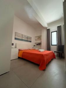 um quarto com uma cama com um cobertor laranja em Mare a KmZERO em Gallipoli