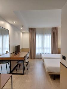 Cette chambre comprend un bureau, un lit et une table. dans l'établissement Hotel Costa Atlántica, à Arteixo