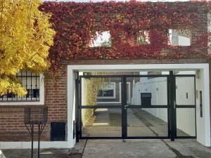 an open garage door with red ivy on a brick building at Departamento dos dormitorios con cochera Tres Arroyos -3- in Tres Arroyos