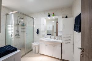 baño blanco con ducha y lavamanos en George's Paradise, en Afantou