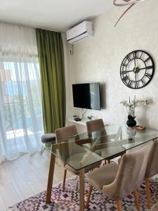 una sala da pranzo con tavolo in vetro, sedie e orologio di Apartments Tivat a Tivat