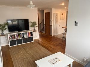 a living room with a flat screen tv on a entertainment center at 1min walk to Beach- Happy Waves- Family Home in Camber