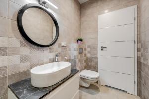 a bathroom with a white sink and a mirror at KALVARI APARTMENTs in Vilnius