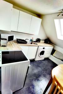 a kitchen with white cabinets and a washing machine at Cozy Loft In The Heart Of Kirkwall in Orkney
