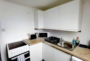 a small kitchen with white cabinets and a sink at Cozy Loft In The Heart Of Kirkwall in Orkney