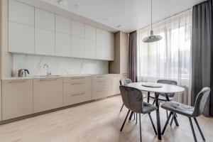 een keuken met witte kasten en een tafel en stoelen bij KALVARI APARTMENTs in Vilnius