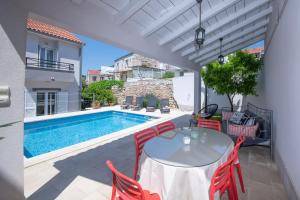 eine Terrasse mit einem Tisch und Stühlen sowie einem Pool in der Unterkunft Villa Mediterana in Vis