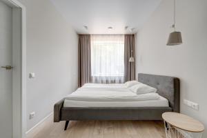 łóżko w białym pokoju z oknem w obiekcie KALVARI APARTMENTs w Wilnie