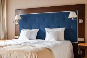 duże łóżko z niebieskim zagłówkiem i białymi poduszkami w obiekcie Villa Garden Dyplomat w Olsztynie