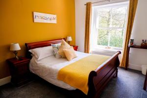 a bedroom with a bed with yellow walls and a window at Greendale Teahouse and Rooms in Chatburn
