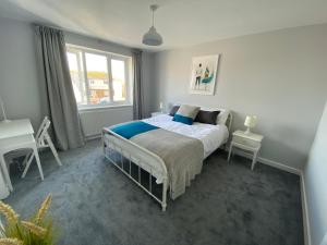 a bedroom with a bed and a desk and a window at 1min walk to Beach- Happy Waves- Family Home in Camber