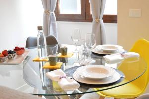 una mesa de cristal con platos y vasos. en Casa Annabel en Pavia