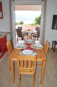 a wooden table with chairs and a table with glasses on it at Apartments Mija in Pridraga