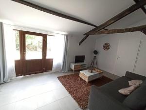 ein Wohnzimmer mit einem Sofa, einem TV und einer Tür in der Unterkunft Magnifique pigeonnier rénové classé 3 étoiles in Catus