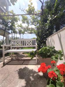 a white bench sitting on a patio with red flowers at Apartman Mila in Novi Vinodolski