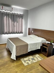 a bedroom with a large bed and a table at Nantes Executive Hotel in Pitanga +22 photos